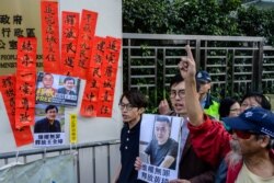 FILE - Hong Kong pro-democracy activists hold a placard, at right, that reads "rights activism is not wrong, free Huang Qi" during a protest outside the Chinese Liaison Office in Hong Kong, Jan. 29, 2019.