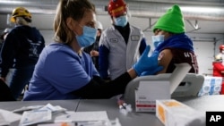 FILE - A Tyson Foods team member receives a COVID-19 vaccine from health officials at the Joslin, Illinois facility, Feb. 19, 2021. 