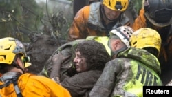 Emergency personnel carry a woman rescued from a collapsed house after a mudslide in Montecito, California, Jan. 9, 2018. 