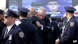 A couple of police officers embrace as they arrive for the funeral mass of New York City police officer Brian Moore, May 8, 2015, at the St. James Roman Catholic church in Seaford, N.Y. 