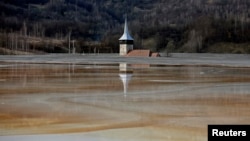 FILE - The old church of Geamana village is partially submerged by polluted water tainted with cyanide and other chemicals near Rosia Montana, central Romania, March 24, 2014. 