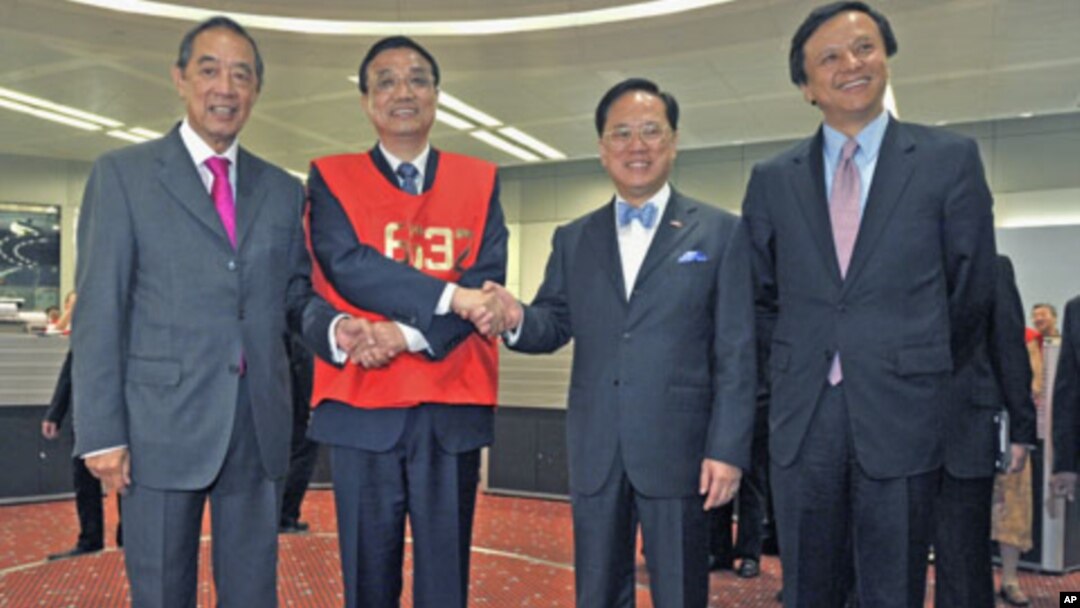 Chinese Vice Premier Li Keqiang (2nd L), wearing a floor trader's vest, poses with Hong Kong Stock Exchange Chairman Ronald Arculli (L), Chief Executive Charles Li (R) and Hong Kong Chief Executive Donald Tsang during his visit to the Hong Kong Stock Exch