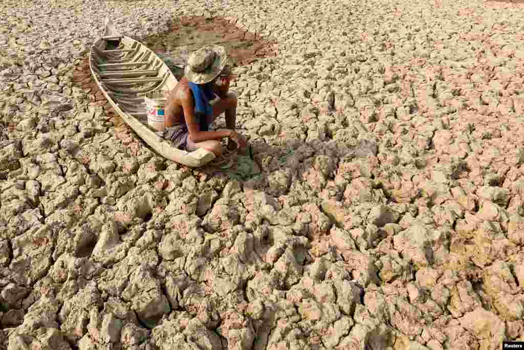 A fisherman sits on his boat on a Bak Angrout dried up pond in the drought-hit Kandal province, Cambodia.