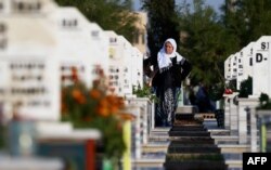 A woman stands in a cemetery during the funeral for a Syrian Democratic Forces fighter killed in Hajin during battles against the Islamic State group, in the Kurdish-controlled city of Qamishly in northeastern Syria, Dec. 3, 2018.