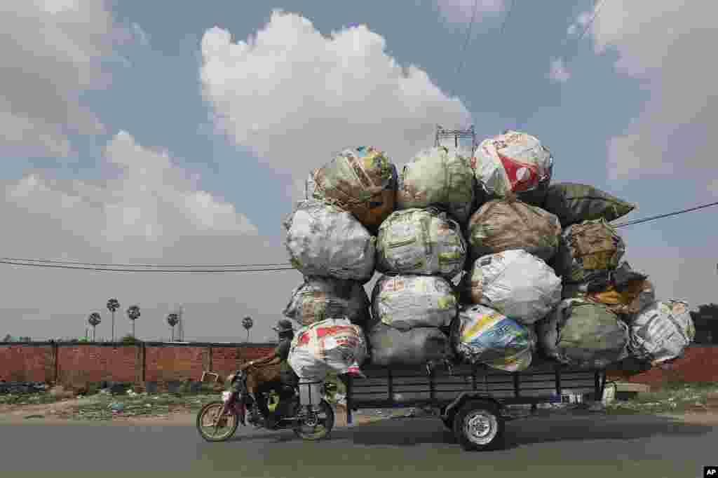 A biker carrying huge bags of recyclables travels on a street outside Phnom Penh, Cambodia.