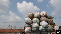 A biker carrying huge bags of recyclables travels on a street outside Phnom Penh, Cambodia.
