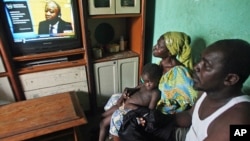 Adama Fofana, who says two of his brothers were killed in post-election violence and their bodies dumped in a mass grave, watches the televised trial of former Ivorian President Laurent Gbagbo, Feb. 19, 2013. 