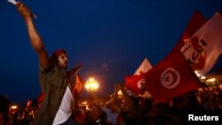 An anti-government protester shouts slogans as others wave flags and signs during a demonstration at Kasbah Square where the government headquarters are located, to call for the departure of the Islamist-led ruling coalition, in Tunis, Aug. 31, 2013.