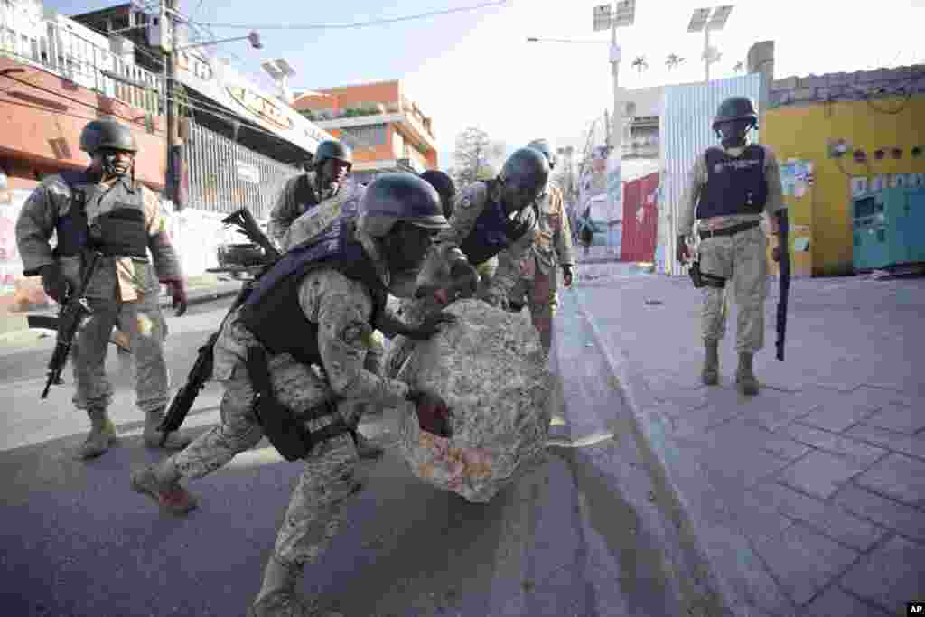 National police officers remove a rock used as a street barricade by demonstrators, after a protest against the results of Oct. 25 elections, in Port-au-Prince, Haiti, Nov. 18, 2015. 