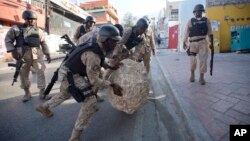 FILE - National police officers remove a rock used as a street barricade by demonstrators, after a protest against the results of Oct. 25 elections, in Port-au-Prince, Haiti, on Nov. 18, 2015. 