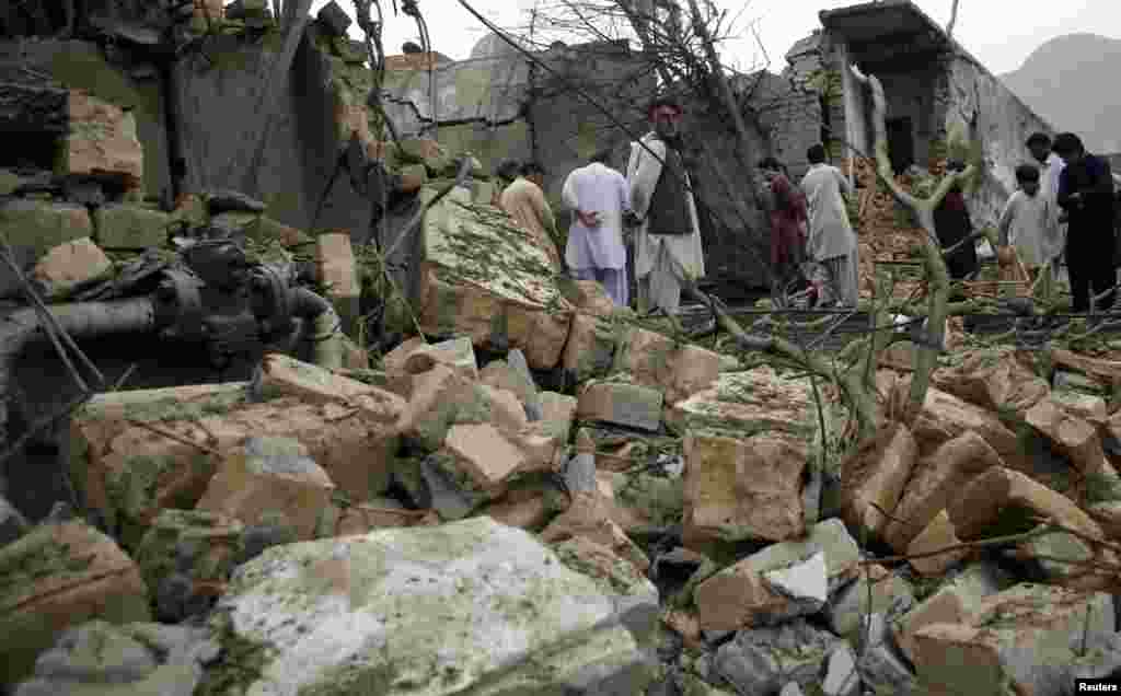 Residents stand among rubble and debris at the site of a bomb attack in Quetta, Pakistan, April 24, 2013. 
