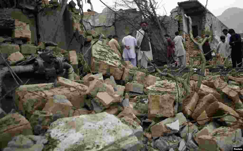 Residents stand among rubble and debris at the site of a bomb attack in Quetta, Pakistan, April 24, 2013.