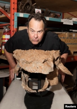 Actor Dan Aykroyd poses in the Royal Ontario Museum's paleontology collections room with fossils of Zuul crurivastator, a new species of armored dinosaur named after the beast Zuul from the film “Ghostbusters” at the Royal Ontario Museum in Toronto, Canada, April 21, 2017.