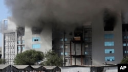 Employees leave as smoke rises from a fire at Serum Institute of India, the world's largest vaccine maker that is manufacturing the AstraZeneca/Oxford University vaccine for the coronavirus, in Pune, Jan. 21, 2021.