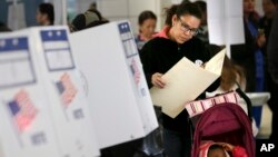 FILE - A woman looks over her ballot at a polling station in the Washington Heights section of New York, Nov. 8, 2016.