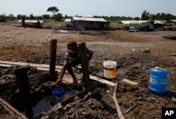 Fisherman Raimundo Silva do Carmo, 67, gets water to drink from a well dug into the dry bed of Puraquequara Lake amid a severe drought, in Manaus, Amazonas state, Brazil, Thursday, Oct. 5, 2023. (AP Photo/Edmar Barros)