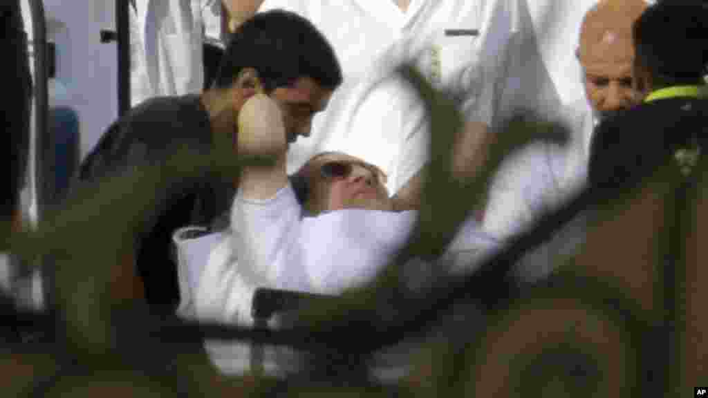 Egyptian medics escort former Egyptian President Hosni Mubarak into an ambulance after after he was flown by a helicopter to the Maadi Military Hospital from Torah prison, Cairo, August 22, 2013.