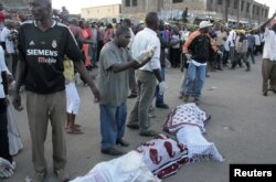 Residents prepare to carry the slain body of a woman killed during an explosion in a passenger mini-bus (matatu) in the Eastleigh neighbourhood of Kenya's capital Nairobi, November 18, 2012.