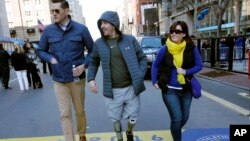 FILE - Boston Marathon bombing survivor Jeff Bauman, center, walks over the marathon finish line on the third anniversary of the bombings, April 15, 2016, in Boston.