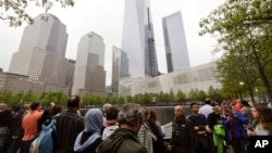 Esta foto de archivo del 15 de mayo del 2015 muestra a un grupo de gente cerca de los monumentos conmemorativos del Memorial del 11 de Septiembre en Nueva York. (AP Foto/Frank Franklin II/Archivo)