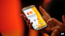 FILE - A woman uses the system Masterpass for payment with phones at the Mobile World Congress, the world's largest mobile phone trade show in Barcelona, Spain, Feb. 25, 2014. 