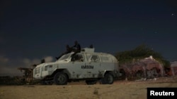 FILE - AMISOM soldiers rest atop armored vehicle during break on street patrol with local police, Mogadishu, Nov. 14, 2013.