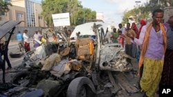 Somalis gather near the wreckage of a car used in an attack outside a beachfront restaurant in Mogadishu, Somalia, Aug. 26, 2016. Experts call for a unified counterterrorism effort. 