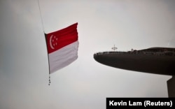 Bendera nasional Singapura dikibarkan oleh helikopter Chinook CH-47SD Angkatan Udara Republik Singapura saat melewati kasino Marina Bay Sands dan Skypark resor. (Foto: REUTERS/Kevin Lam)