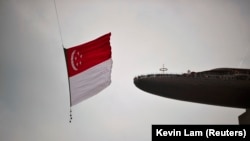 Bendera nasional Singapura dikibarkan oleh helikopter Chinook CH-47SD Angkatan Udara Republik Singapura saat melewati kasino Marina Bay Sands dan Skypark resor. (Foto: REUTERS/Kevin Lam)
