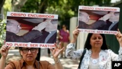 FILE - Members of the movement Laity of Osorno hold up images showing the Rev. Fernando Karadima, left, and his protege Juan Barros, bishop of Osorno, with a message that reads in Spanish: "A bishop who covers up cannot be a priest," during a protest in front of the Apostolic Nunciature in Santiago, Chile, Jan. 12, 2018.