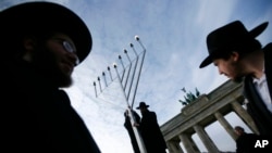 FILE - Rabbis install a giant Hanukkah Menorah at the launch of the eight-day Jewish Festival of Lights, named Hanukkah, in front of the Brandenburg Gate in Berlin, Germany.