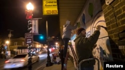 Un residente de Ferguson pinta un mural luego de dos noches de protestas por la decisión del Gran Jurado en el caso de Michael Brown.