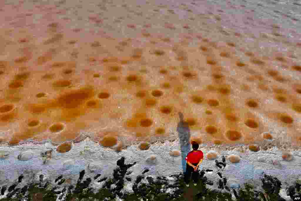 An aerial view shows a man looking at pink colored salt fields, caused by lack of rain, in Tainan, Taiwan.
