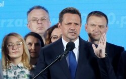 El alcalde de Varsovia, Rafal Trzaskowski (centro) reacciona a las encuestas a boca de urna luego del cierre de votaciones el domingo, 28 de junio de 2020. Trzaskowski se enfrentará al presidente Andrzej Duda en una segunda vuelta el 12 de julio.