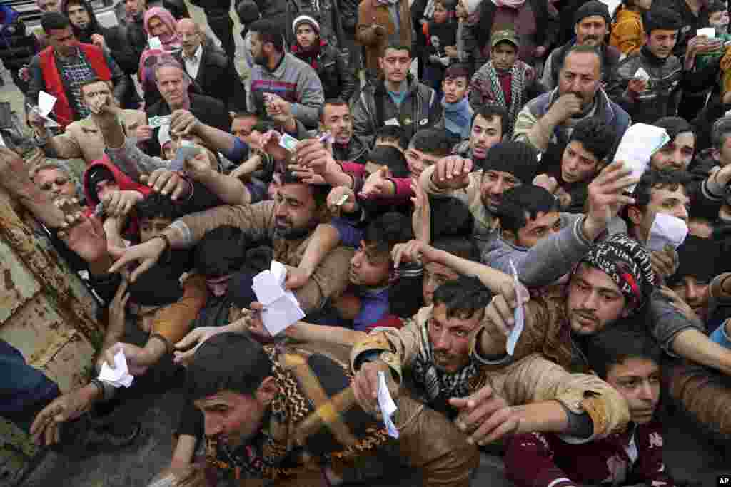 Civilians present their rations cards to receive humanitarian food aid being distributed by the Iraqi Red Crescent, in the eastern side of Mosul.