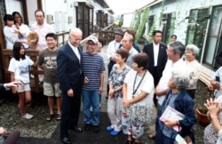 FILE - In this Aug. 23, 2011, Vice President Joe Biden, center left in a dark suit, has a light moment with survivors of the March 11 earthquake and tsunami during his visit to Natori.