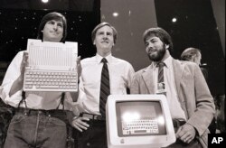 FILE - In this April 24, 1984, file photo, Steve Jobs, left, chairman of Apple Computers, John Sculley, center, president and CEO, and Steve Wozniak, co-founder of Apple, unveil the new Apple IIc computer in San Francisco.