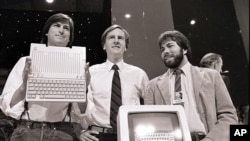 ARCHIVO - En esta foto de archivo del 24 de abril de 1984, Steve Jobs, presidente de Apple Computers, John Sculley, centro, presidente y CEO, y Steve Wozniak, cofundador de Apple, presentan la nueva computadora Apple IIc en San Francisco . Apple cumplió 40 años, y es una compañía muy diferente de la audaz startup que Jobs y Wozniak lanzaron en un garaje de Silicon Valley en 1976. (AP Photo / Sal Veder, Archivo).