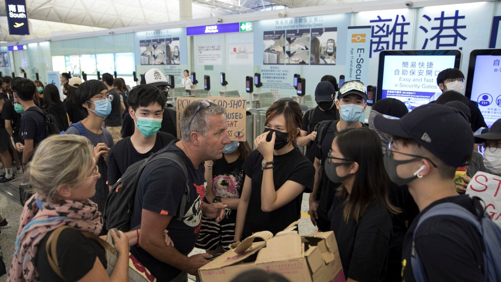 Putnici se raspravljaju sa demonstrantima dok pokušavaju da prođu kroz aerodromske odlazne gejtove, na međunarodnom aerodromu u Hong Kongu, 13. avgusta 2019.