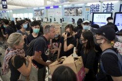 Travelers argue with protesters as they try to go through the departure gates of the Hong Kong International Airport in Hong Kong, Aug. 13, 2019.