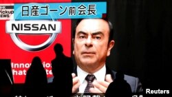 FILE - Passersby are silhouetted as a huge street monitor broadcasts news reporting ousted Nissan Motor chairman Carlos Ghosn's indictment and re-arrest in Tokyo, Japan, Dec. 10, 2018.