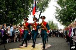 FILE - Schoolchildren watch as servicemen carry a flag of the Russia-backed self-proclaimed separatist Donetsk republic, at a ceremony on the first day of school in Donetsk, Ukraine, Sept. 1, 2017.