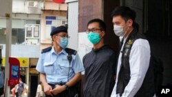 FILE - Simon Leung Kam-wai, center, a committee member of the Hong Kong Alliance in Support of Patriotic Democratic Movements of China, is escorted by police during an investigation of the June 4th Museum in Hong Kong. 