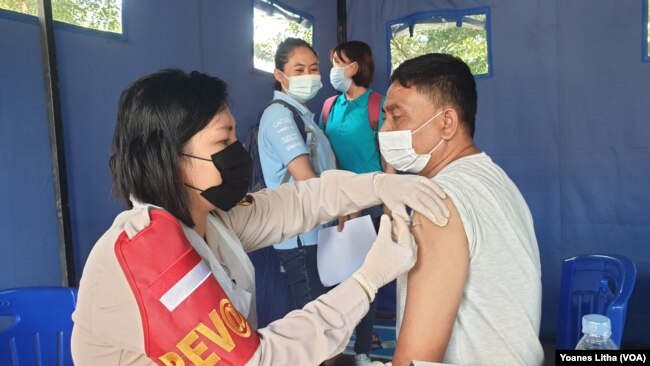 Petugas Kesehatan Polda Sulawesi Sulawesi Tengah saat memberikan vaksinasi COvid-19 bagi warga Kota Palu di Taman GOR, Kota Palu. Jumat (4/6/2021). (Foto: VOA/Yoanes Litha)