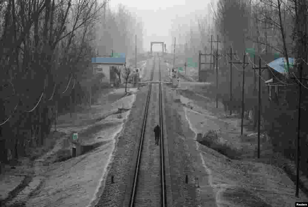 A man walks on a frost-covered railway track on a cold winter morning on the outskirts of Srinagar.