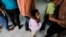 FILE - Women and their children wait in line to register at the Honduran Center for Returned Migrants.
