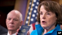 Senate Intelligence Committee Vice Chair Sen. Dianne Feinstein (r) joined by Sen. Ben Cardin, left, points to the embedded chip in her passport that contains digital information, as she and other Democrats talk about security measures for Syrian refugees and others coming into the U.S., Nov. 19, 2015, during a news conference on Capitol Hill in Washington.