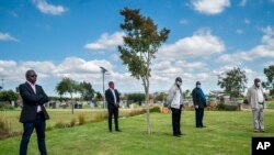 Family and friends observe social distancing during the funeral for Benedict Somi Vilakasi at the Nasrec Memorial Park outside Johannesburg, April 16, 2020. South Africa is under a five-week lockdown in a effort to fight the coronavirus pandemic.