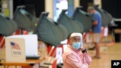 지난 6월 예비선거(프라이머리)가 열린 미국 텍사스주 휴스턴의 투표소에서 진행요원이 신종 코로나바이러스 감염을 막기 위해 보호장비를 착용하고 있다.