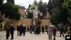 Visitors admire a massive, 13-meter replica of the statue of Roman Emperor Constantine that was built using 3D technology from scans of the nine giant original marble body parts that remain. Tuesday, Feb. 6, 2024.(AP Photo/Andrew Medichini)